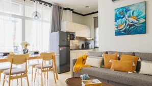 Ein modernes Wohnzimmer mit einem grauen Sofa, Holzstühlen, einem Couchtisch und einem Bild an der Wand.