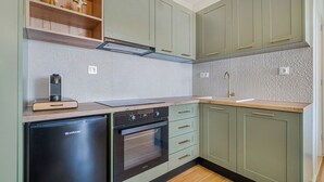 A kitchen with green cabinets, a black dishwasher, a built-in oven, and a wooden countertop.