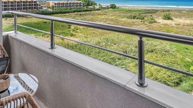 A balcony with a view of the beach and mountains.