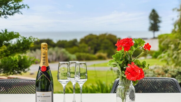 Ett bord med en flaska Moët & Chandon-champagne, tre glas och en vas med röda blommor.