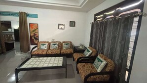 A living room with a sofa set, a coffee table, and a patterned curtain. - OYO 95050 Penginapan Sekarsari Syariah (Yogyakarta)