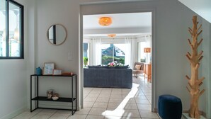 Una sala de estar moderna con un sofá, una mesa de centro, una escultura de madera y vistas al exterior.