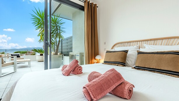 A hotel room with a large bed, two rolled towels, a wooden headboard, and a view of the outdoors. - A Terrazzo di Calypso - Grande Terrasse (Grosseto-Prugna)