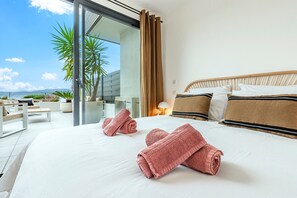 A hotel room with a large bed, two rolled towels, a wooden headboard, and a view of the outdoors. - A Terrazzo di Calypso - Grande Terrasse (Grosseto-Prugna)