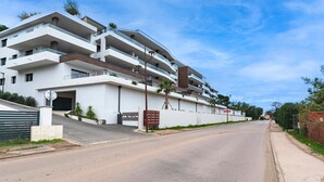 A multi-story residential building with balconies, a gated entrance, and a clear sky. - A Terrazzo di Calypso - Grande Terrasse (Grosseto-Prugna)