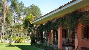 Ein Haus mit überdachter Terrasse, Ziegelmauern und einem gepflegten Rasen.