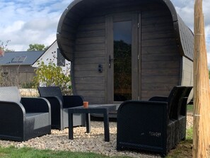 Een houten blokhut met een gebogen dak, een tafel en twee stoelen.
