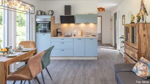 Eine moderne Küche mit einer zentralen Kochinsel, eingebauten Geräten und einem Essbereich mit Holztisch und Stühlen.