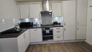 A kitchen with white cabinets, a black stove, and a microwave. - Stylish 2 Bed Flat Near Airpot with free parking (Edinburgh)