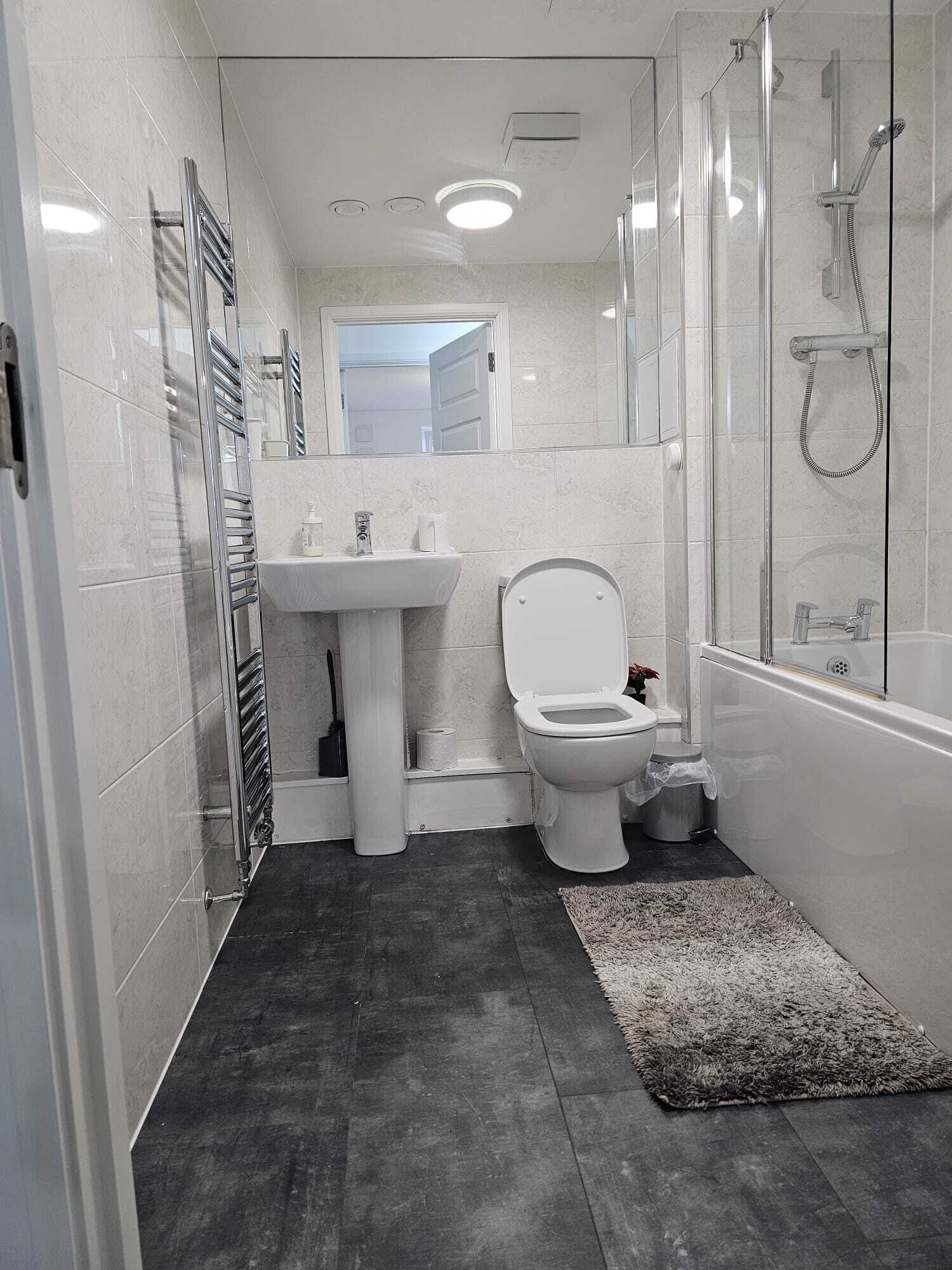 A modern bathroom with a glass shower enclosure, a white sink, and a toilet.