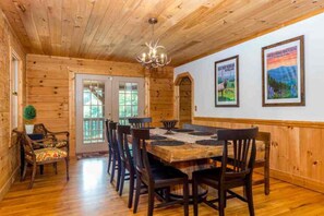 A wooden interior with a dining table, chairs, a chandelier, and framed pictures on the wall. - Lionheart Cabin-Majestic Mountain Escape,Game Room (Maggie Valley)