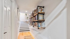 Um corredor com escadas, estante de livros e uma planta em vaso.