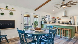 Una cucina moderna con isola centrale, travi in legno al soffitto e un cartello di benvenuto appeso al muro.