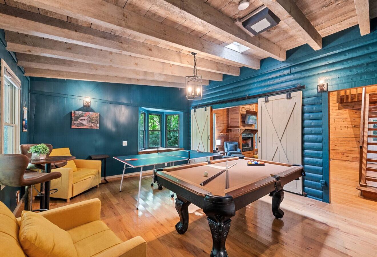 A cozy indoor space with a pool table, yellow sofas, and a wooden ceiling.