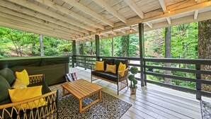 Una terraza al aire libre con piso de madera, un sofá, una silla y una mesa.