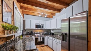 Una cocina moderna con encimeras de granito, electrodomésticos de acero inoxidable y vigas de madera en el techo.