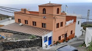 Ein Küstengebäude mit Flachdach, Steinmauer und Blick auf das Meer.