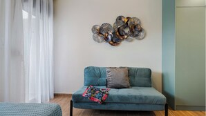 Moderni olohuone, jossa on turkoosinsininen sohva, värikäs abstrakti taideteos seinällä ja puulattia.