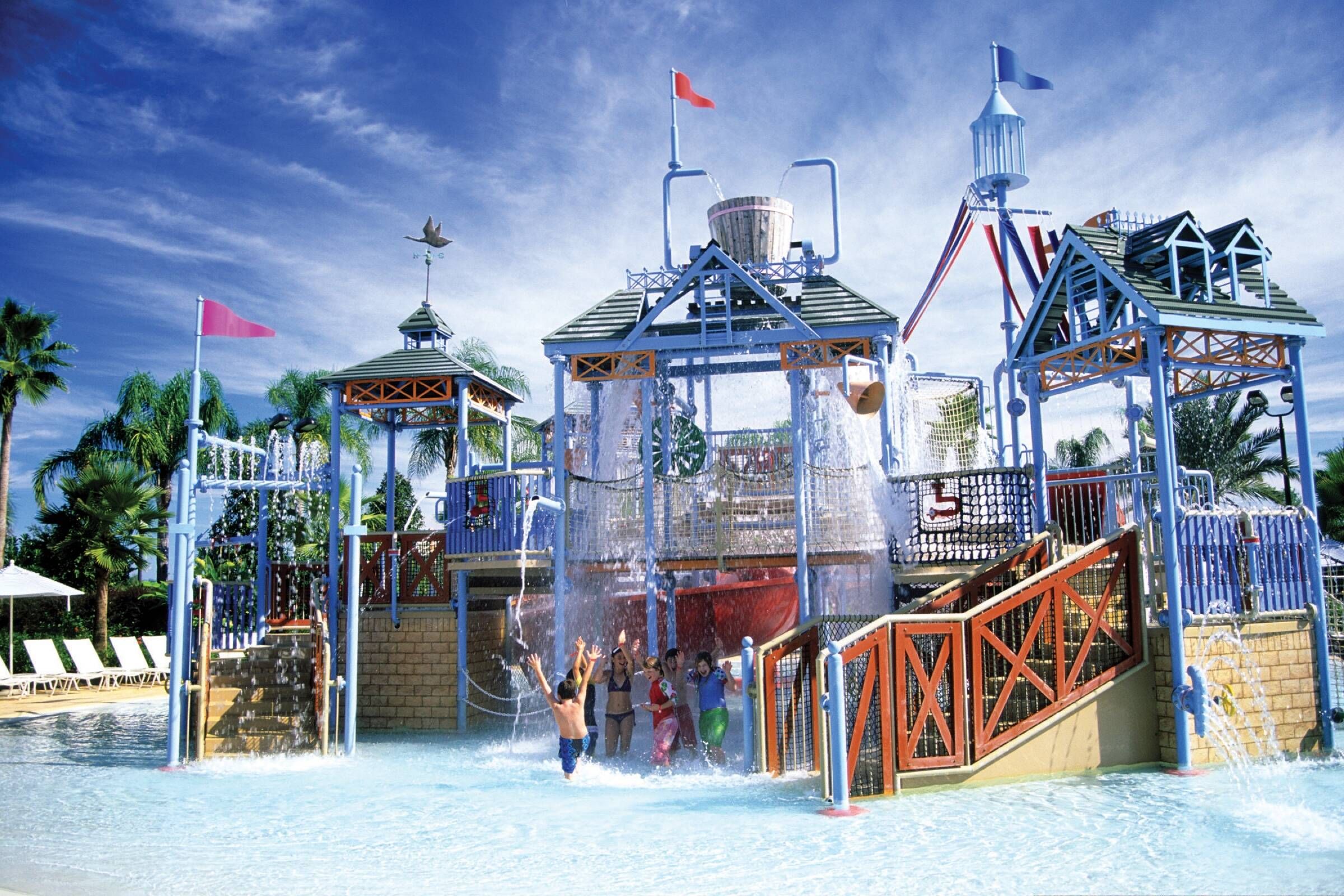 Een waterpark met diverse speelconstructies, waaronder een golfslagbekken en een glijbaan.