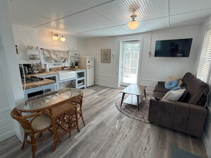 A compact living space with a kitchen, dining area, and a seating area with a sofa and a TV. - Old Florida Fish Camp (Cedar Key)