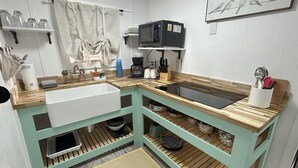 A kitchen with a sink, microwave, and various utensils. - Old Florida Fish Camp (Cedar Key)