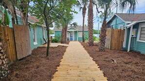 A wooden pathway leading to a row of cabins with a clear sky above. - Old Florida Fish Camp (Cedar Key)