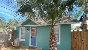 A small house with a blue door, a wooden deck, and a palm tree in the yard. - Old Florida Fish Camp (Cedar Key)