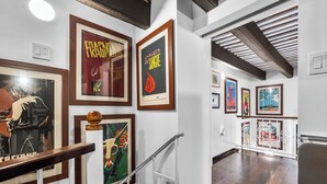 Eine Galerie mit gerahmten Kunstwerken an den Wänden und einer Holztreppe.