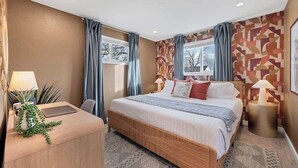 A modern hotel room with a large bed, a desk with a laptop, and a small side table. - Game Room, Cinema & Fire Pit Backyard (Denver)