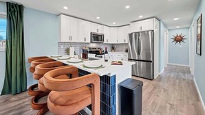 A modern kitchen with white cabinets, stainless steel appliances, and a central island with seating. - Game Room, Cinema & Fire Pit Backyard (Denver)