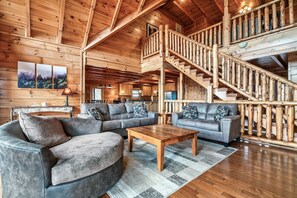 A log cabin interior with a living room, a staircase, and a kitchen. - Timber Sky Lodge! Elevator/Pool/Theater | Sleep 27 (Sevierville)