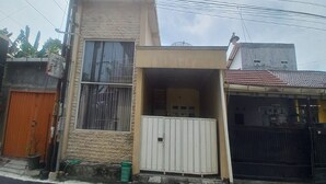A two-story building with a small porch and a garage. - OYO 95060 Ahzafani Homestay Syariah (Lemahireng)