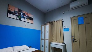 A hotel room with a bed, a desk, a wardrobe, and a wall-mounted air conditioner. - OYO 95060 Ahzafani Homestay Syariah (Lemahireng)