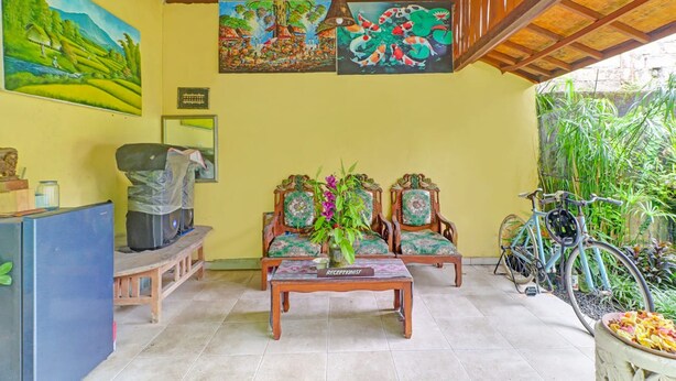 A reception area with a wooden reception desk, two chairs, and a wall with two paintings. - OYO 95060 Ahzafani Homestay Syariah (Lemahireng)