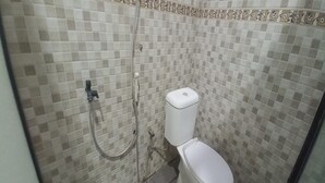 A bathroom with a toilet, a shower, and a tiled wall. - OYO 95060 Ahzafani Homestay Syariah (Lemahireng)