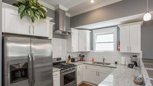 A modern kitchen with white cabinets, stainless steel appliances, granite countertops, and a built-in stove. - Spacious Nashville Family Home| Perfect for Groups (Nashville)