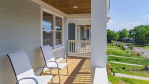 A covered porch with two white chairs, a wooden deck, and a view of a residential street. - Spacious Nashville Family Home| Perfect for Groups (Nashville)