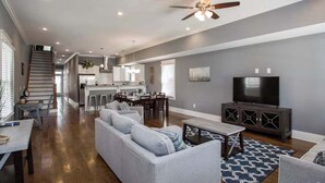 A spacious living room with a grey sofa, a dining area, a kitchen, and a TV. - Spacious Nashville Family Home| Perfect for Groups (Nashville)