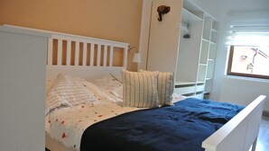 Een bed met een wit hoofdeinde, gestreepte kussens en een donkerblauwe deken.