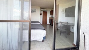 A room with two beds, a dining table, and a kitchen area. - Cozy Studio apartment in tranquil Cancún with AC (Cancún)