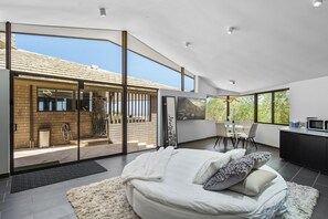 Une chambre moderne dotée d’un grand lit, d’un coin repas et offrant une vue sur l’extérieur.