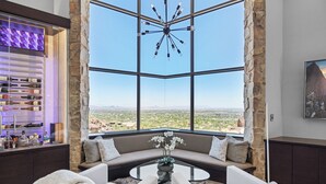 A modern living room with a large window, a wine rack, and a seating area with a view of the desert. - Camelback Valley / Mountain Views, Pool & Hot Tub (Paradise Valley)