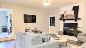 A living room with a grey sofa, a coffee table, and a fireplace. - Southern Magnolia 3BR/2Bath Home 5 min to base (Enterprise)