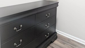 A closet with a black dresser and a hanging rod above. - Southern Magnolia 3BR/2Bath Home 5 min to base (Enterprise)