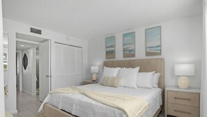 A modern bedroom with a large bed, bedside tables, and a walk-in closet. - Beach Luxury Retreat • Walk to Beach & 5th Ave (Naples)