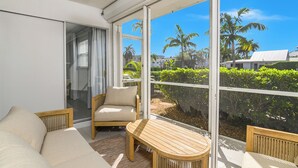 A balcony with a sofa, a wooden table, and a chair. - Beach Luxury Retreat • Walk to Beach & 5th Ave (Naples)