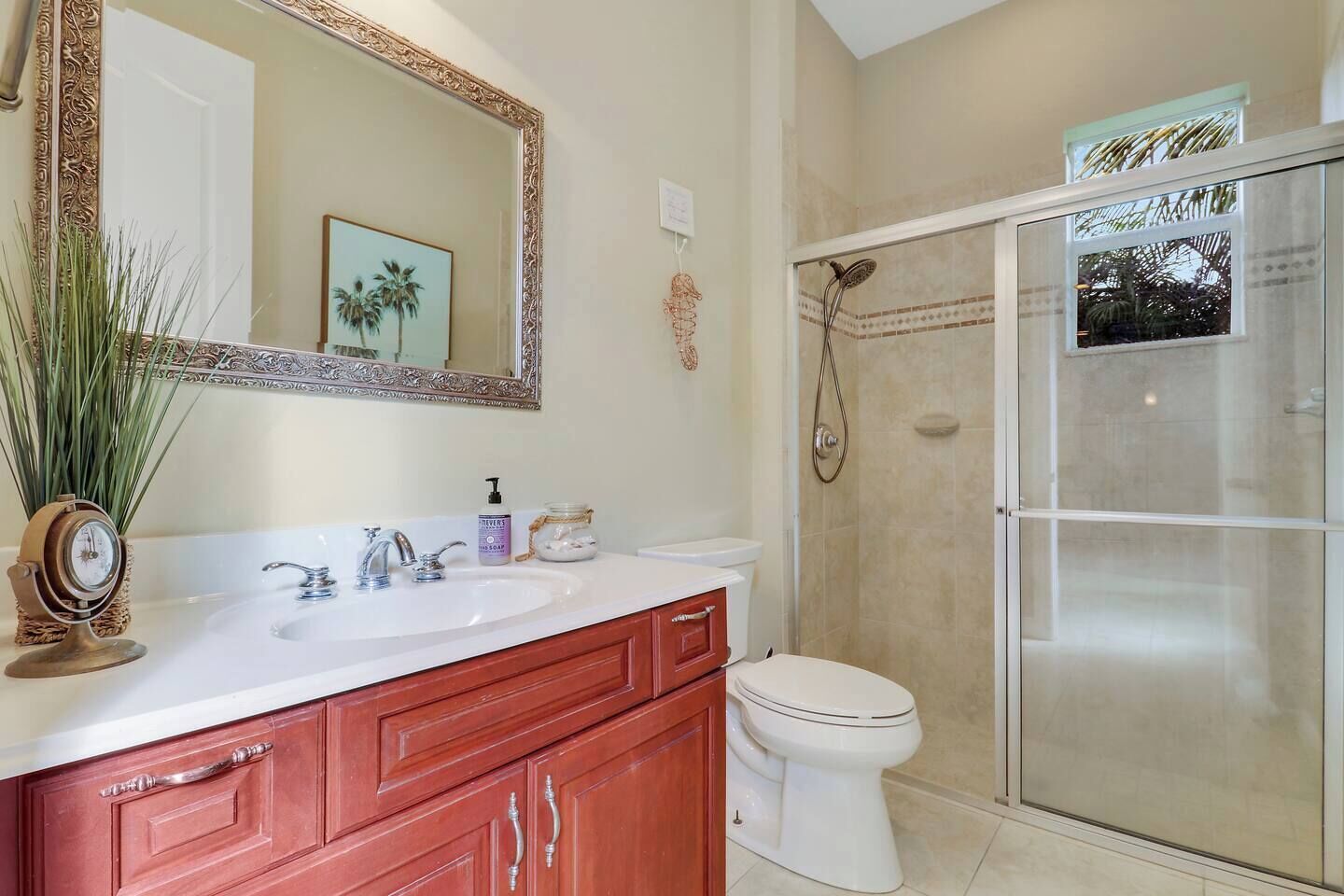 A bathroom with a white sink, a mirror, a toilet, and a glass shower enclosure.