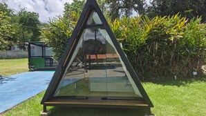 A modern, triangular glass structure in a garden setting. - Cabanas.tur Ilhabela (Ilhabela)
