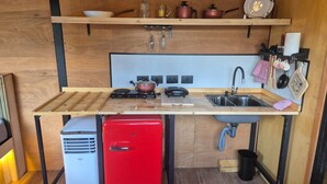 A compact kitchen with a wooden countertop, a red refrigerator, a sink, and various kitchen utensils. - Cabanas.tur Ilhabela (Ilhabela)