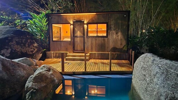 A wooden cabin with a wooden deck, a pool, and a door with windows. - Cabanas.tur Ilhabela (Ilhabela)